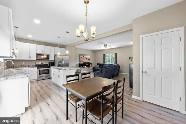 a view of a dining room with furniture a kitchen and chandelier