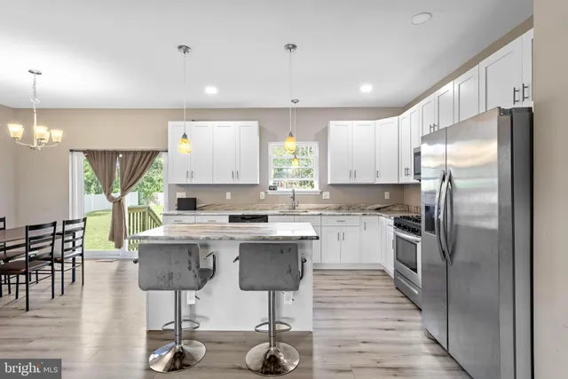 a kitchen with stainless steel appliances kitchen island granite countertop a kitchen island hardwood floor and a sink