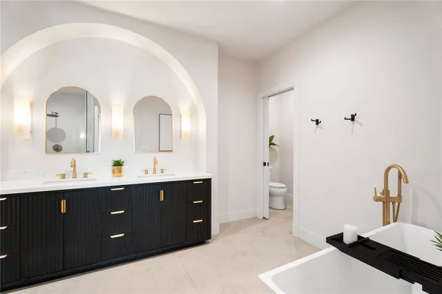 a spacious bathroom with a double vanity sink a mirror and a bathtub