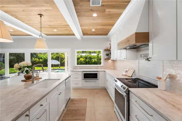 a kitchen with stainless steel appliances a stove a sink and a white cabinets