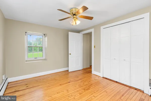 an empty room with wooden floor fan and windows