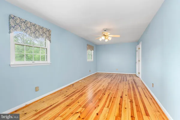 a view of an empty room with wooden floor and windows
