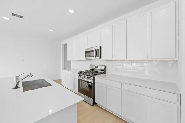 a kitchen with granite countertop white cabinets and stainless steel appliances