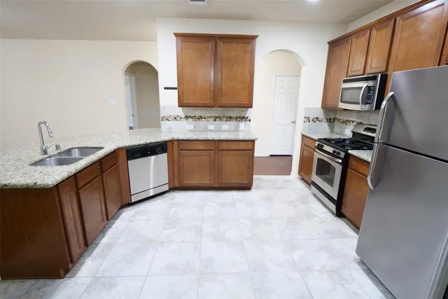 a kitchen with stainless steel appliances granite countertop a sink stove and refrigerator