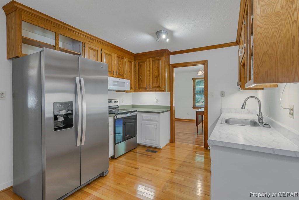 35 Powhatan Road Kilmarnock, VA 22482 - Photo 14 of 42 Kitchen with a sink, light countertops, light wood-style flooring, and appliances with stainless steel finishes