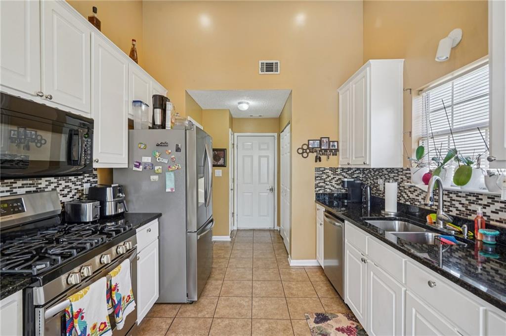 4496 Jackam Ridge Court Lithonia, GA 30038 - Photo 12 of 24 a kitchen with stainless steel appliances granite countertop a stove a refrigerator and a wooden cabinets