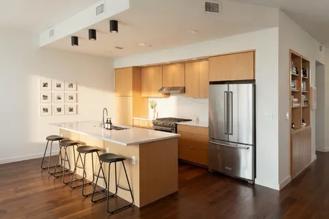 a kitchen with stainless steel appliances a dining table chairs refrigerator and sink