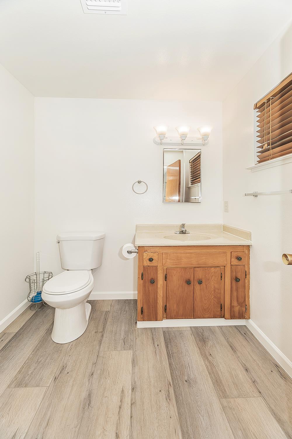 1064 East Early Avenue Reedley, CA 93654 - Photo 16 of 36 a bathroom with a granite countertop toilet a sink and a mirror