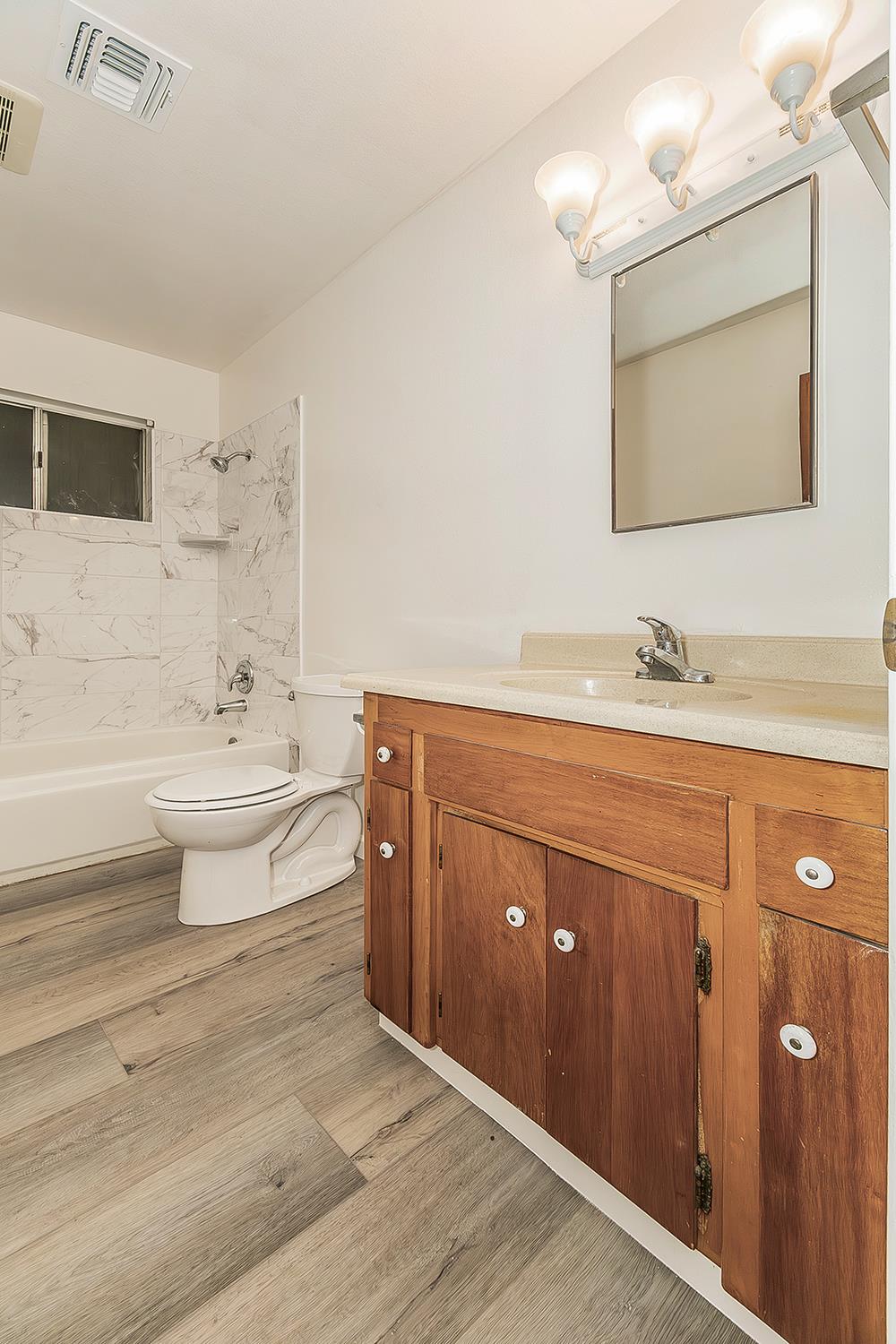 1064 East Early Avenue Reedley, CA 93654 - Photo 23 of 36 a bathroom with a double vanity sink a mirror and a bathtub