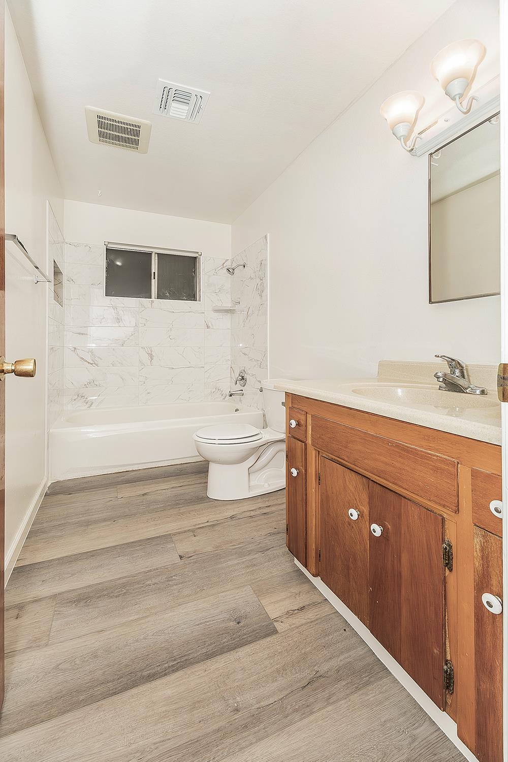 1064 East Early Avenue Reedley, CA 93654 - Photo 24 of 36 a bathroom with a sink toilet a mirror and shower