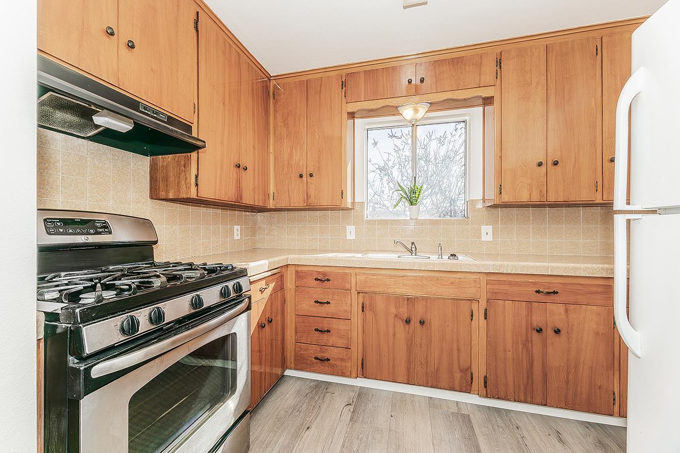 1064 East Early Avenue Reedley, CA 93654 - Photo 7 of 36 a kitchen with wooden cabinets and a stove top oven