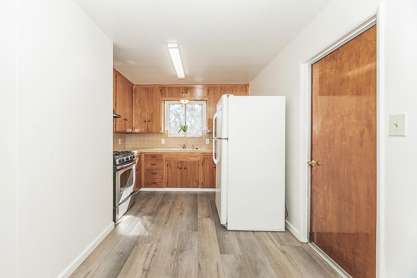 1064 East Early Avenue Reedley, CA 93654 - Photo 8 of 36 a kitchen with a refrigerator a sink and wooden floor