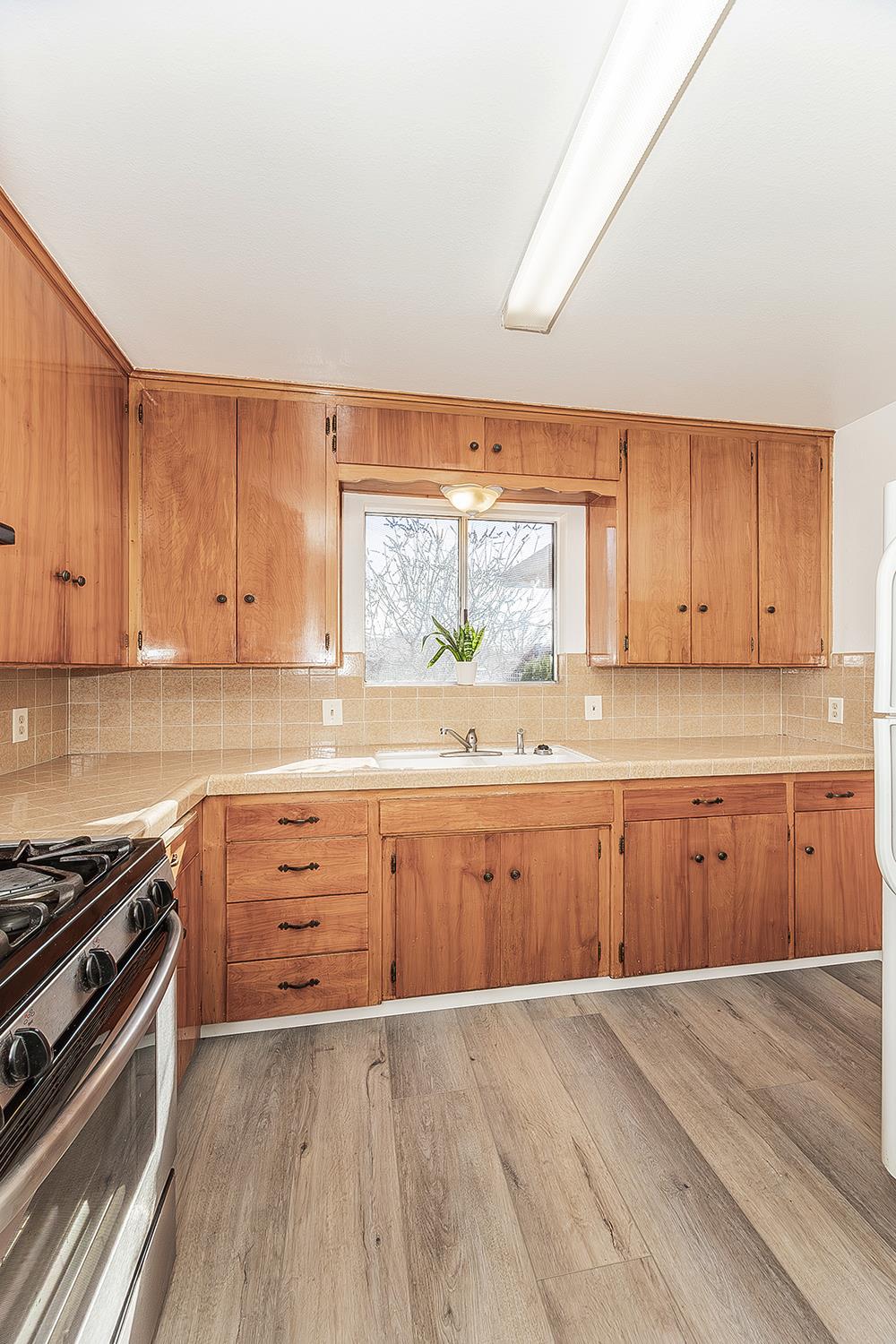 1064 East Early Avenue Reedley, CA 93654 - Photo 10 of 36 a kitchen with wooden cabinets and a stove top oven