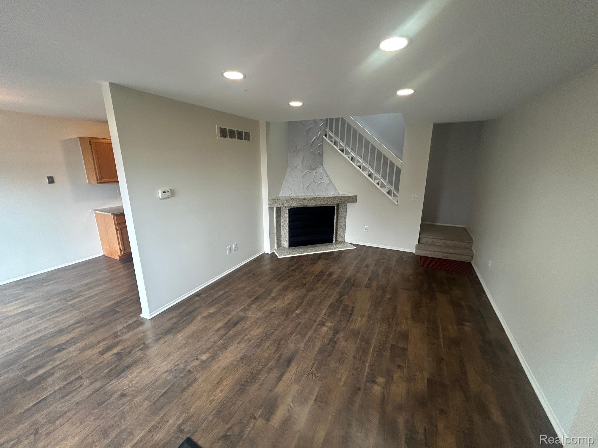 31164 Country Way Farmington, MI 48331 - Photo 6 of 33 Unfurnished living room featuring a fireplace with raised hearth, dark wood-style floors, and recessed lighting