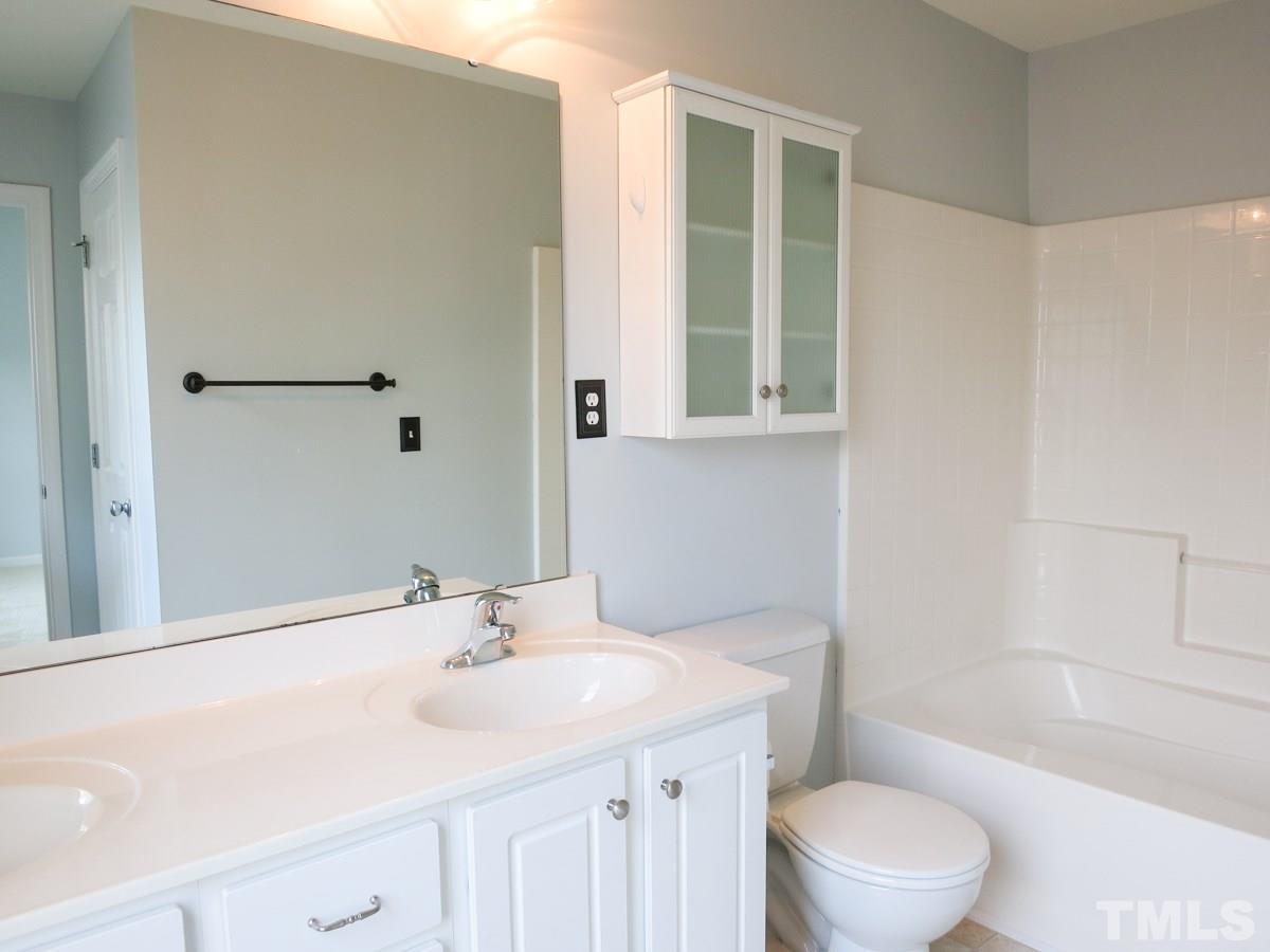 8516 Barryknoll Court Raleigh, NC 27613 - Photo 15 of 25 The lg Master Bath features double sinks, tub/shower, linen closet, neutral vinyl floor & wall cabinet.
