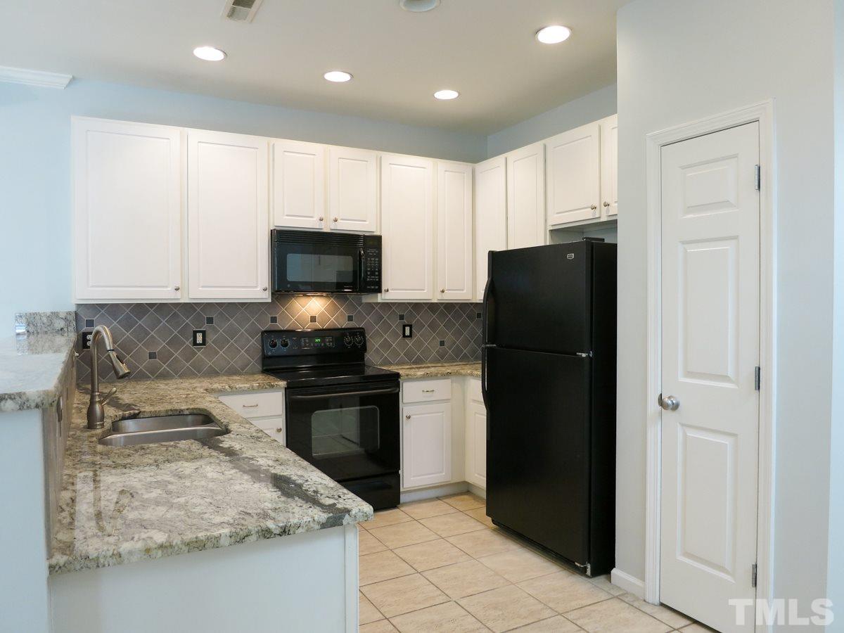 8516 Barryknoll Court Raleigh, NC 27613 - Photo 9 of 25 The updated Kitchen features granite ctrs, 42” white cabinets, tile backsplash, black appls (smooth-top range, MW, DW), neutral tile flr, pantry, recessed lights & tall eat-at bar.
