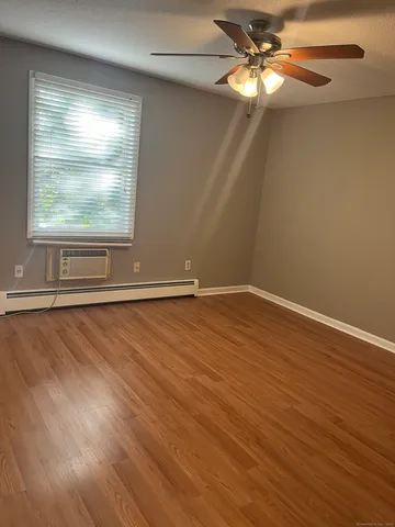 an empty room with wooden floor fan and windows