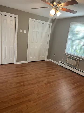 an empty room with wooden floor fan and windows