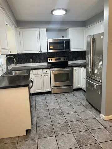 a kitchen with stainless steel appliances granite countertop a stove a refrigerator and a sink