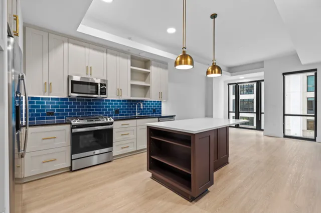 a kitchen with stainless steel appliances granite countertop a stove a sink and a wooden floors