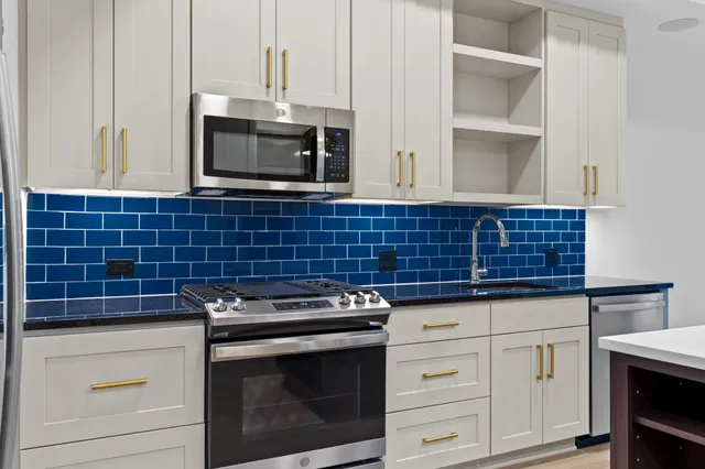 a kitchen with granite countertop white cabinets stainless steel appliances and a sink