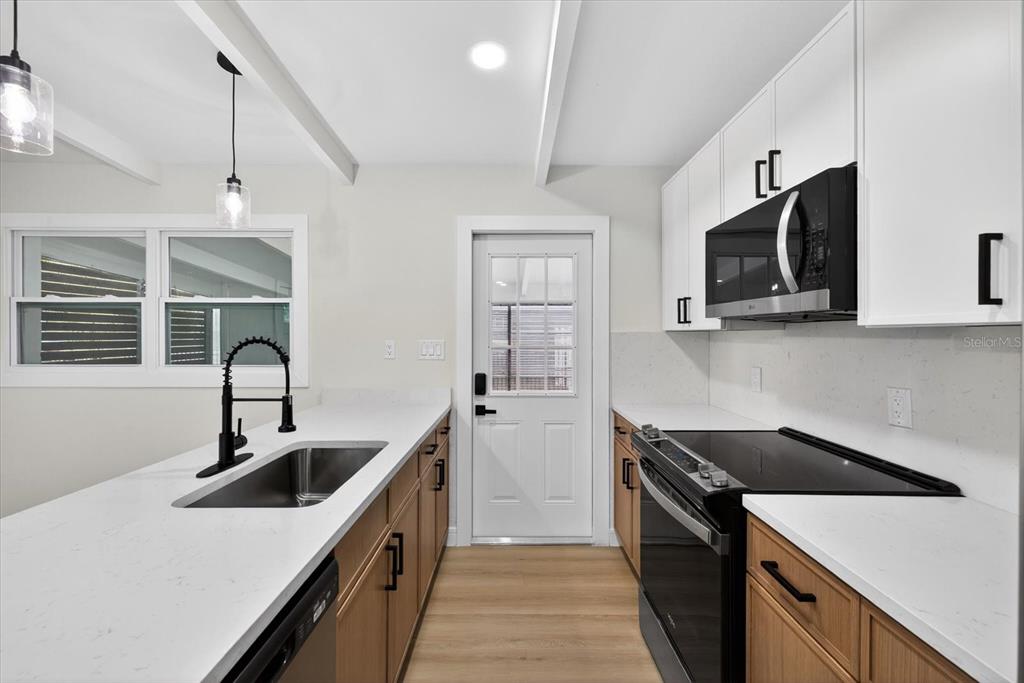 5901 South Coolidge Avenue Tampa, FL 33616 - Photo 17 of 47 a kitchen with stainless steel appliances granite countertop a sink and stove top oven with wooden floor