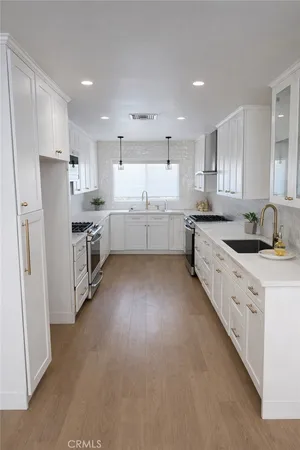 a large kitchen with stainless steel appliances refrigerator a sink dishwasher a stove a microwave oven and white cabinets next to a window