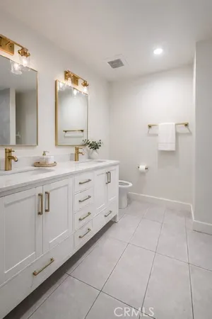 a spacious bathroom with a double vanity sink a mirror and a toilet