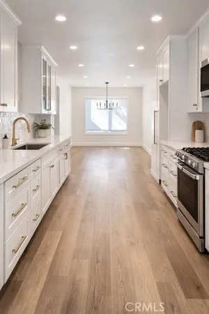 a large kitchen with stainless steel appliances a large counter top a stove a sink and a refrigerator