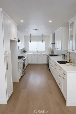 a large kitchen with stainless steel appliances refrigerator a sink dishwasher a stove a microwave oven and white cabinets next to a window