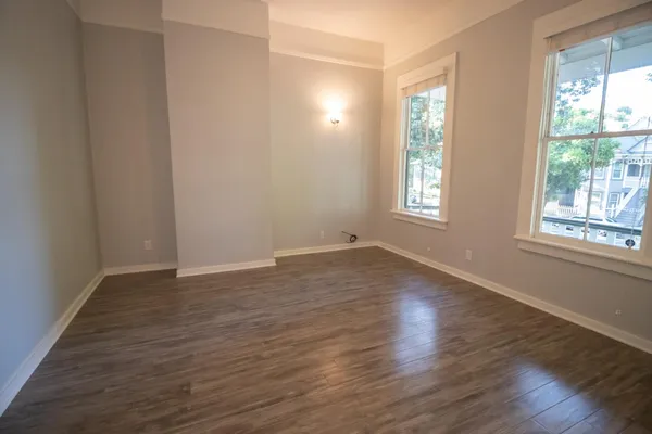 an empty room with wooden floor and windows