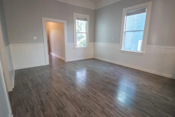 an empty room with wooden floor and windows