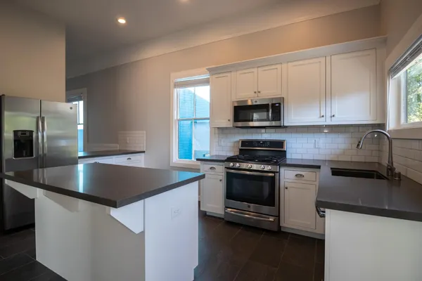 a kitchen with stainless steel appliances granite countertop a sink a stove and a refrigerator