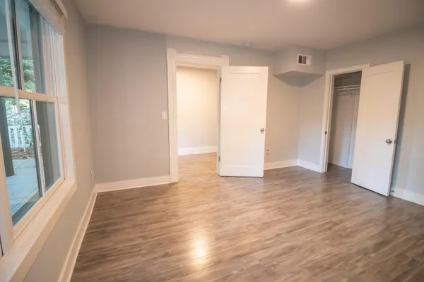 a view of an empty room with wooden floor and a window