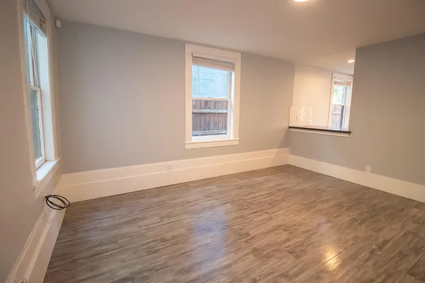 a view of an empty room with wooden floor and a window