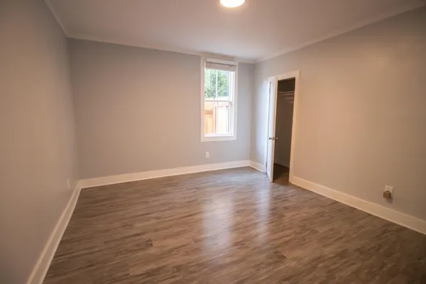 a view of an empty room with wooden floor and window