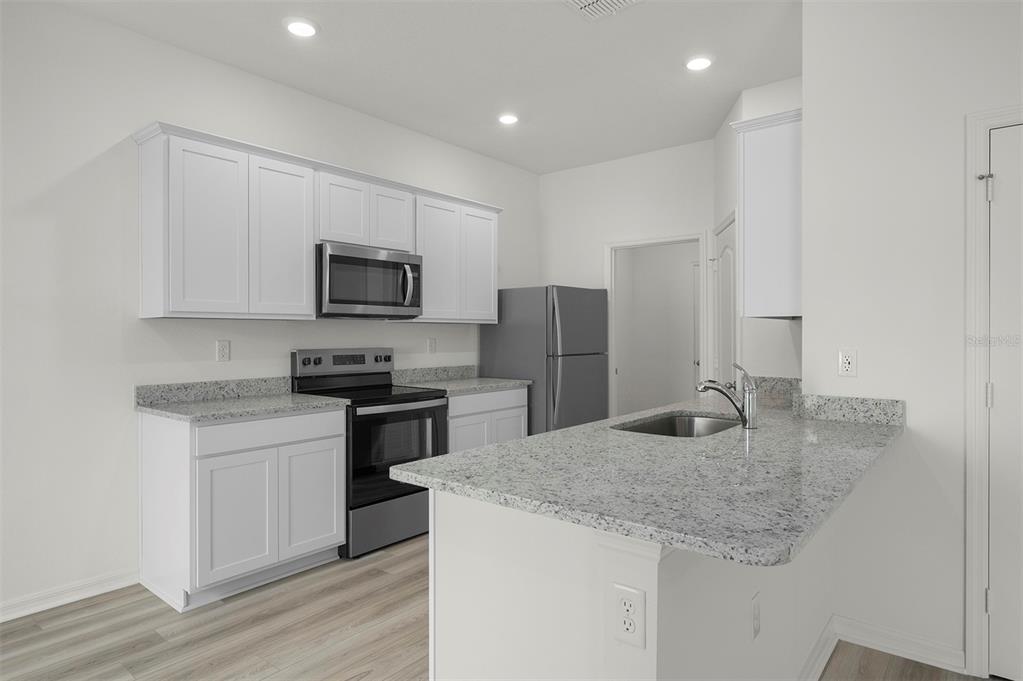 13348 Tula Loop Astatula, FL 34705 - Photo 7 of 22 a kitchen with stainless steel appliances granite countertop a sink stove and refrigerator