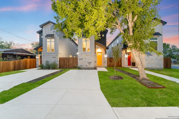 a view of a house with a small yard and a large tree