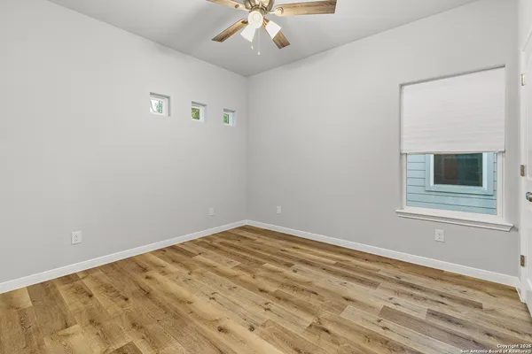 a view of empty room with wooden floor and fan