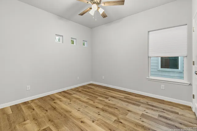 a view of empty room with wooden floor and fan