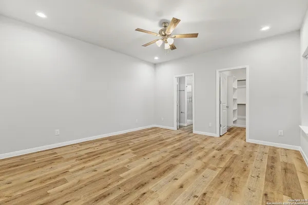 a view of an empty room and chandelier fan