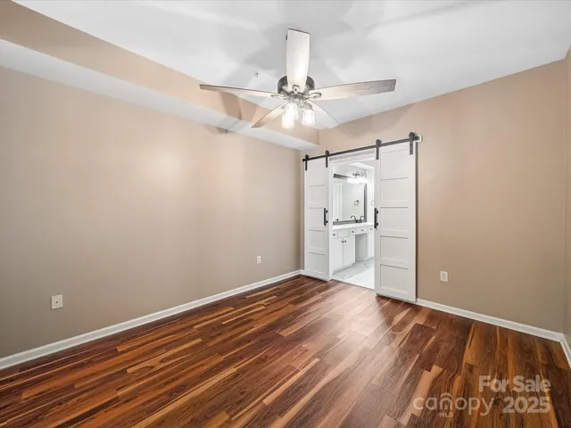 a view of an empty room with wooden floor a ceiling fan and wooden floor