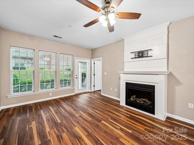 a view of an empty room with wooden floor fireplace and a window