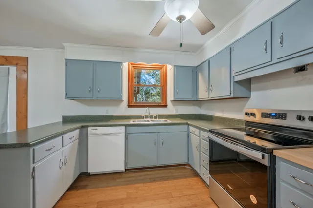 an empty room with chandelier fan and windows
