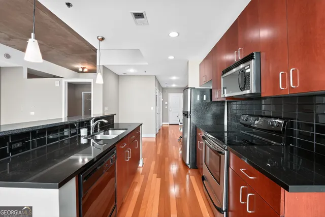 a kitchen with stainless steel appliances granite countertop a sink a stove and a wooden cabinets