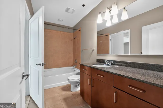 a bathroom with a granite countertop sink a toilet a mirror and shower