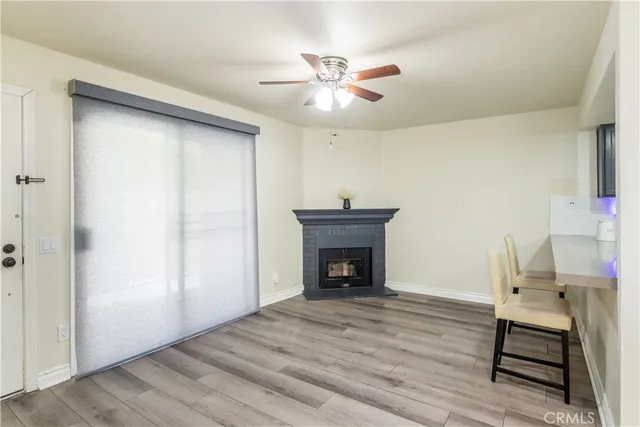 a view of an empty room with wooden floor fireplace and a window