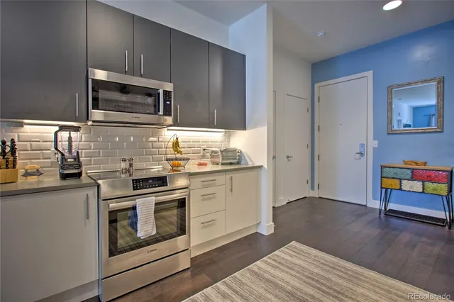 a kitchen with stainless steel appliances white cabinets and wooden floor