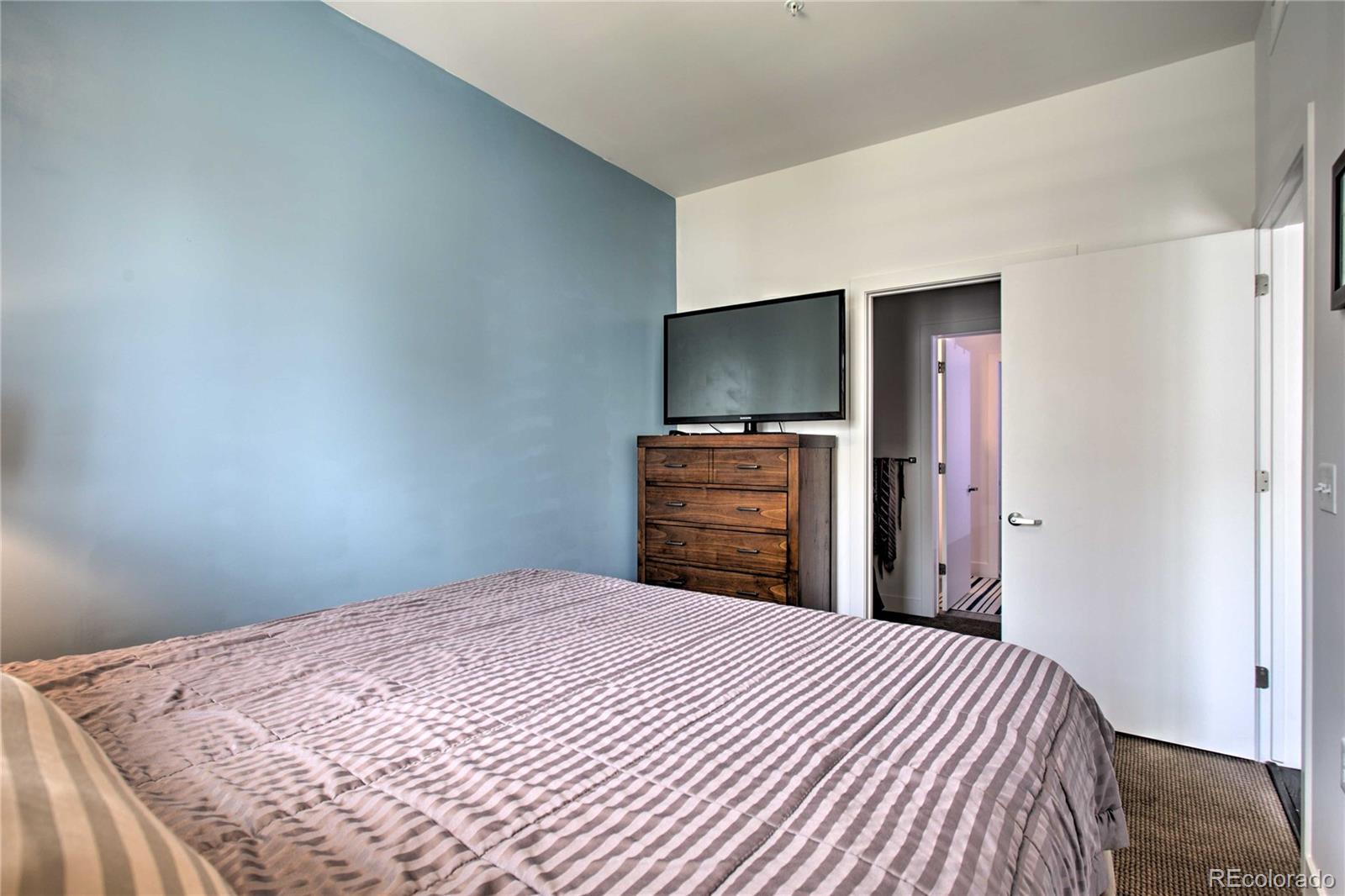 2550 Lawrence Street, Unit RB204 Denver, CO 80205 - Photo 16 of 36 a bedroom with a bed and a flat screen tv
