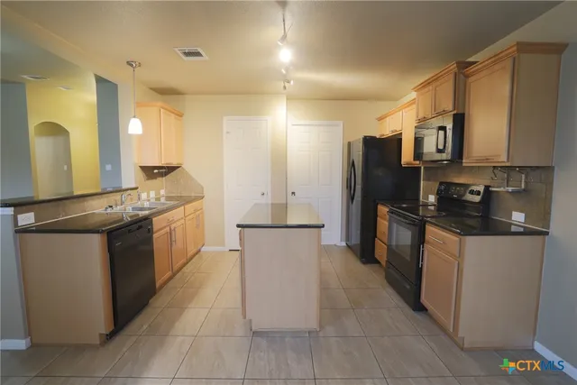 a large kitchen with stainless steel appliances kitchen island granite countertop a refrigerator a stove and a sink